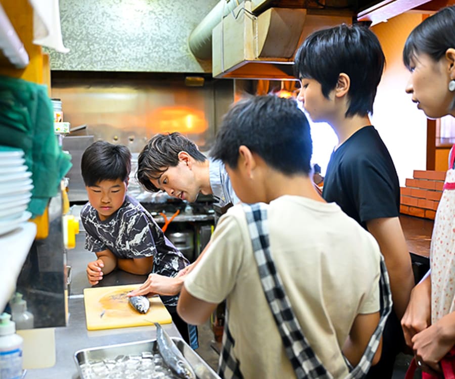 魚の捌き方のお手本を見せている男性